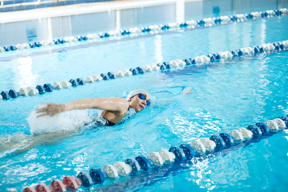 A little girl wearing glasses, a front swimmer crawls into the swimming pool 